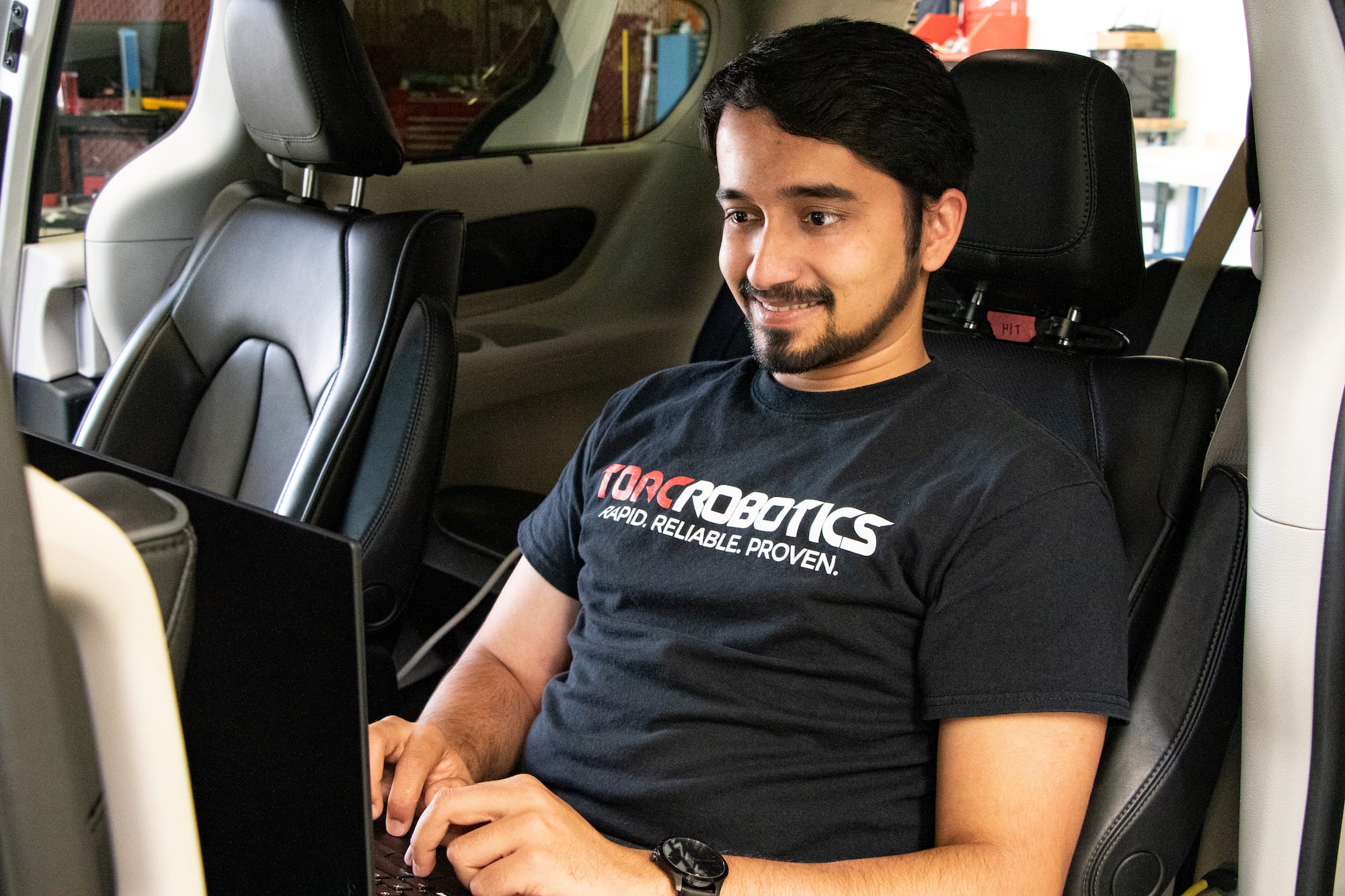 Software engineer working on computer in car