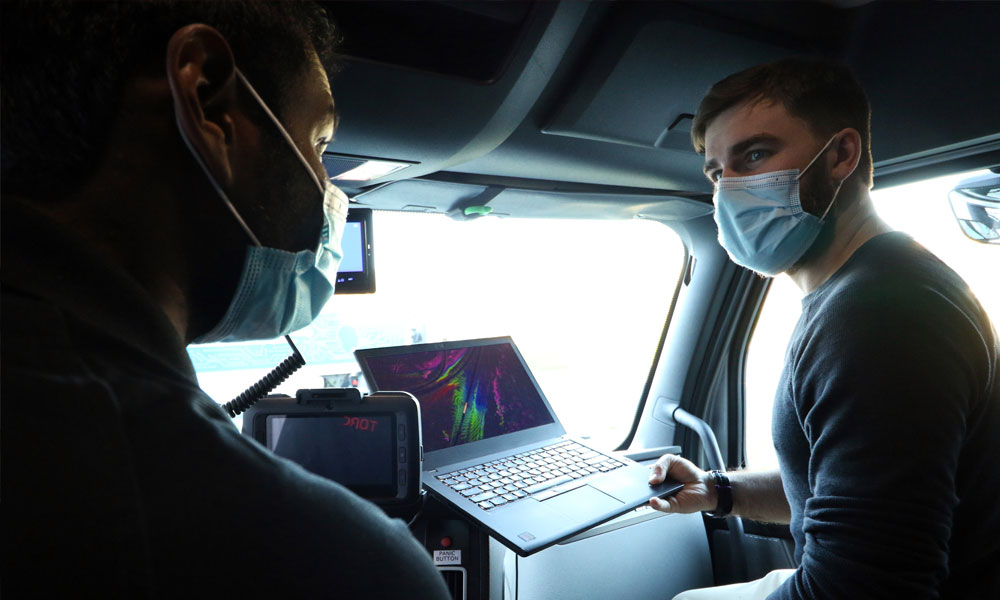 two torc employees sitting in a vehicle with a laptop having a discussion