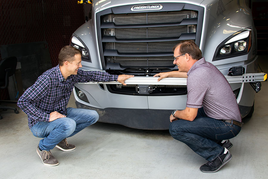 two torc team members looking at the grill of a truck.