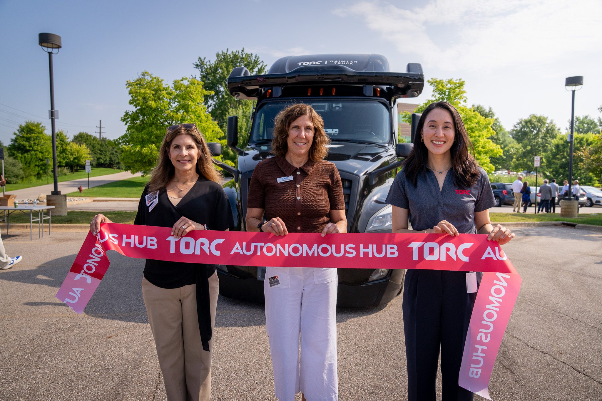 Torc Robotics employees smile as they hold the ribbon during the autonomous trucking company's Ann Arbor office opening.